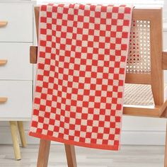 a red and white checkered blanket sitting on top of a wooden chair