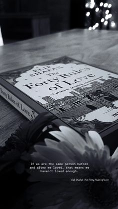 a book sitting on top of a wooden table next to a vase with flowers in it