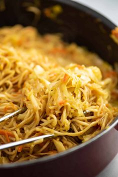 a pan filled with noodles and carrots on top of a table