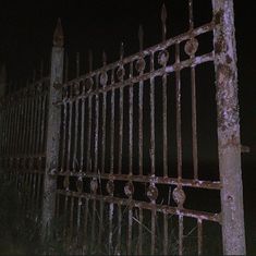 an old iron fence is lit up at night