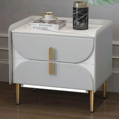 a white nightstand with a black and gold vase on top