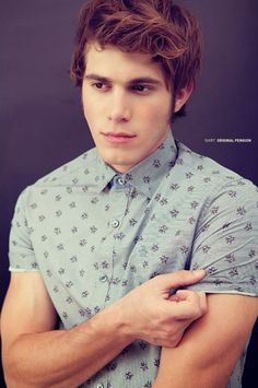 a young man with his arms crossed posing for a photo in front of a black background