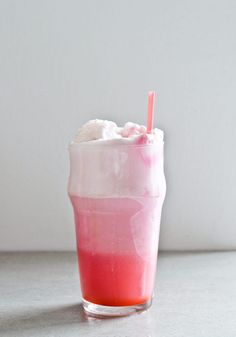 a pink drink with whipped cream and a straw