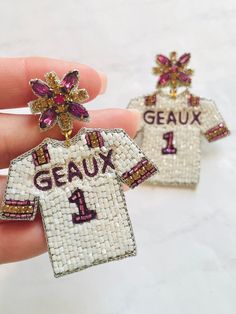 Louie Love Brand Exclusive  Discover Bold Style with Our Beaded Sports Team 'Geaux' Baseball Jersey Earrings Make a fashion statement with our exquisite Hand Beaded Sports Theme 'Geaux' Baseball Jersey Earrings. Crafted with attention to detail, these handmade earrings showcase detailed sports theme.  Materials and Design: Each earring features a meticulously beaded detail, ensuring both durability and lightweight comfort for all-day wear. The intricate beadwork detailing adds a touch of flair to any gameday outfit. Pair of "GEAUX" "GEAUX" Gameday Fashion Accessory: Whether you're heading to a gameday part or tailgating at your favorite sporting event, these earrings are the perfect accessory to elevate your ensemble. Pair them with your favorite gameday outfit tee for an effortlessly chic Gameday Fashion, Diy Bead Embroidery, Gifts For Sports Fans, Trendy Accessories, Accessories Earrings, Purple Gold, Hand Beading, Diy Beads, Handmade Earrings