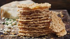 a stack of crackers sitting on top of a wooden cutting board next to cheese