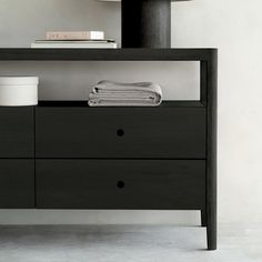 a black dresser with two drawers and a lamp