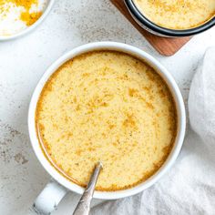 two bowls filled with soup on top of a white counter next to a wooden cutting board