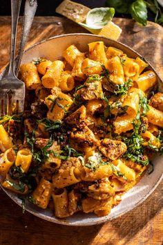 a bowl filled with pasta and spinach on top of a wooden table