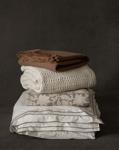 three blankets stacked on top of each other in front of a dark background with white and brown accents