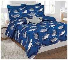 a bed covered in blue and white sheets with shark design on it's side