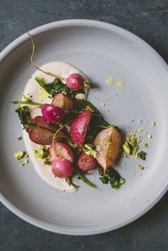 a white plate topped with radishes on top of a green leafy salad