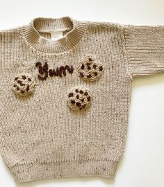 Cute Cookie hand embroidered knit sweatshirt. This sweatshirt features hand embroidered cookies & 'Yum' stitching, adding a playful twist to  an everyday essential.  This sweatshirt comes in soft & light cotton blend knit material, making it ideal for all year round.  The speckled oatmeal colour makes this sweatshirt versitile and able to be styled with any outfit!  Available in 6-12M, 12-18M, 2-3Y & 3-4Y Cute Fitted Crew Neck Sweater, Fitted Cute Crew Neck Sweater, Fitted Crew Neck Sweater In Cute Style, Playful Knitted Cotton Tops, Fitted Cotton Cream Sweater, Fitted Cream Cotton Sweater, Embroidered Cream Cotton Sweater, Cream Cotton Embroidered Sweater, Cream Embroidered Cotton Sweater