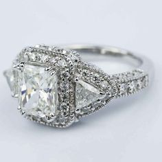 an engagement ring with three princess cut diamonds on the sides and pave set shoulders