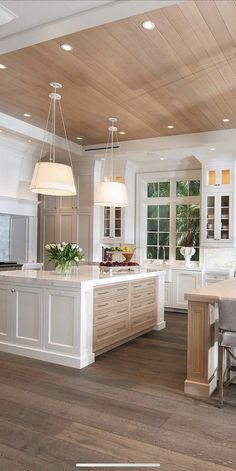 a large open kitchen with white cabinets and wood flooring on the walls, along with an island