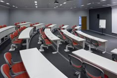 an empty classroom with rows of desks and chairs in front of a projector screen