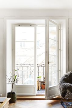 an open door leading to a balcony with potted plants on the floor and in front of it