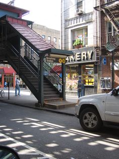 a white truck parked on the side of a road next to a building with stairs