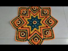 an orange and blue crocheted rug sitting on top of a white tile floor