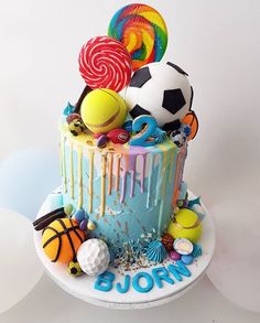 a birthday cake decorated with sports balls and lollipops