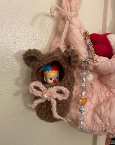 a stuffed bear hanging from the side of a pink coat on a hook with a doll in it