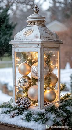 a lantern with ornaments and lights on it in the snow