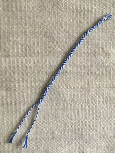 a piece of blue thread is on top of a gray cloth with a crochet hook