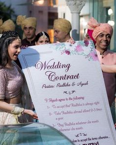 the bride and grooms are holding up a sign for their guests to take pictures