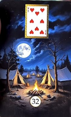 a person holding up a playing card in front of a campfire