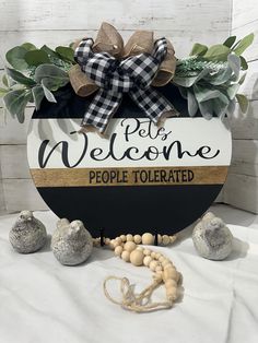 a welcome sign surrounded by rocks and greenery on a white sheeted tablecloth