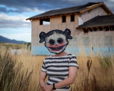 a person wearing a clown mask standing in front of a house