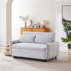 a living room with a white couch and potted plant on the side table in front of it