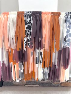 an assortment of scarves are hanging on a rack in front of a white wall