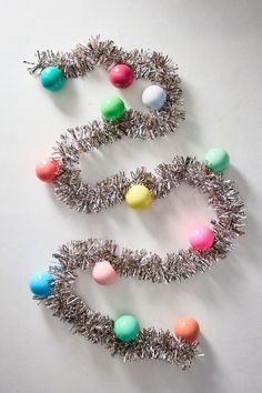 three christmas wreaths with balls and tinsel wrapped around them on a white surface