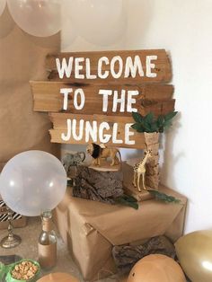 a welcome to the jungle sign on a table with balloons and other items around it