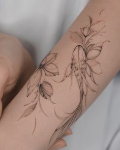 a woman's arm with flowers and leaves tattooed on the side of her arm