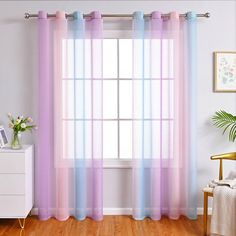 a living room with a window covered in purple and blue sheer curtain panels next to a white dresser