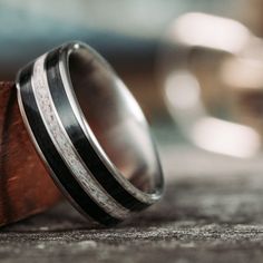 two wedding bands are sitting on top of a wooden ring holder with silver inlays