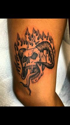 a black and white photo of a demon skull with flames on it's thigh