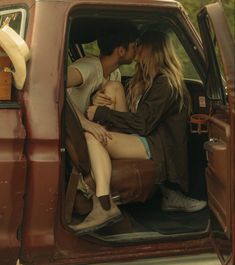 a man and woman sitting in the back of a truck