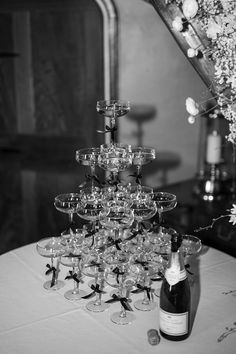 a table topped with lots of wine glasses and a cake stand filled with champagne flutes