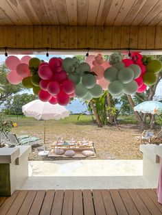 balloons are hanging from the ceiling over an outdoor table