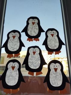 the penguins are made out of construction paper and cut to look like they are standing in front of a window