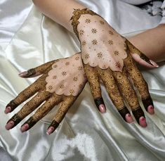 a woman's hands with hennap on top of white satin covered sheets