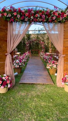 an outdoor wedding ceremony with flowers on the aisle and draping over the doorway