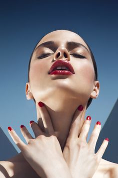 a woman with red nail polish holding her hands up to her face and posing for the camera