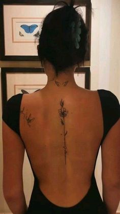 the back of a woman's body with tattoos on her upper and lower back