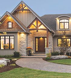 a large house with lots of windows and lights on it's front door, in the evening