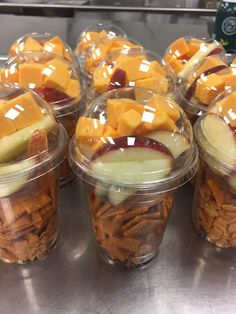 several plastic containers filled with food on top of a metal counter covered in cheese and fruit