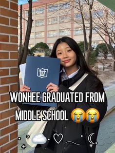 a woman holding up a book in front of a brick wall with the words, wonhee graduate from middle school