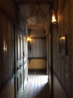 an empty hallway leading to another room with wallpapered walls and wood flooring